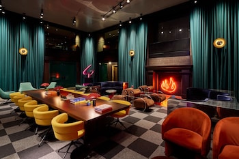 A modern living room with a green sofa, a round coffee table, and a bookshelf with colorful books. at Paramount Times Square – A Generator Hotel