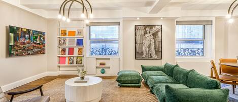 A modern living room with a green sofa, a round coffee table, and a bookshelf with colorful books.