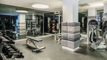 Un gimnasio moderno con diversos equipos de ejercicio, como mancuernas, bancos y máquinas de pesas.