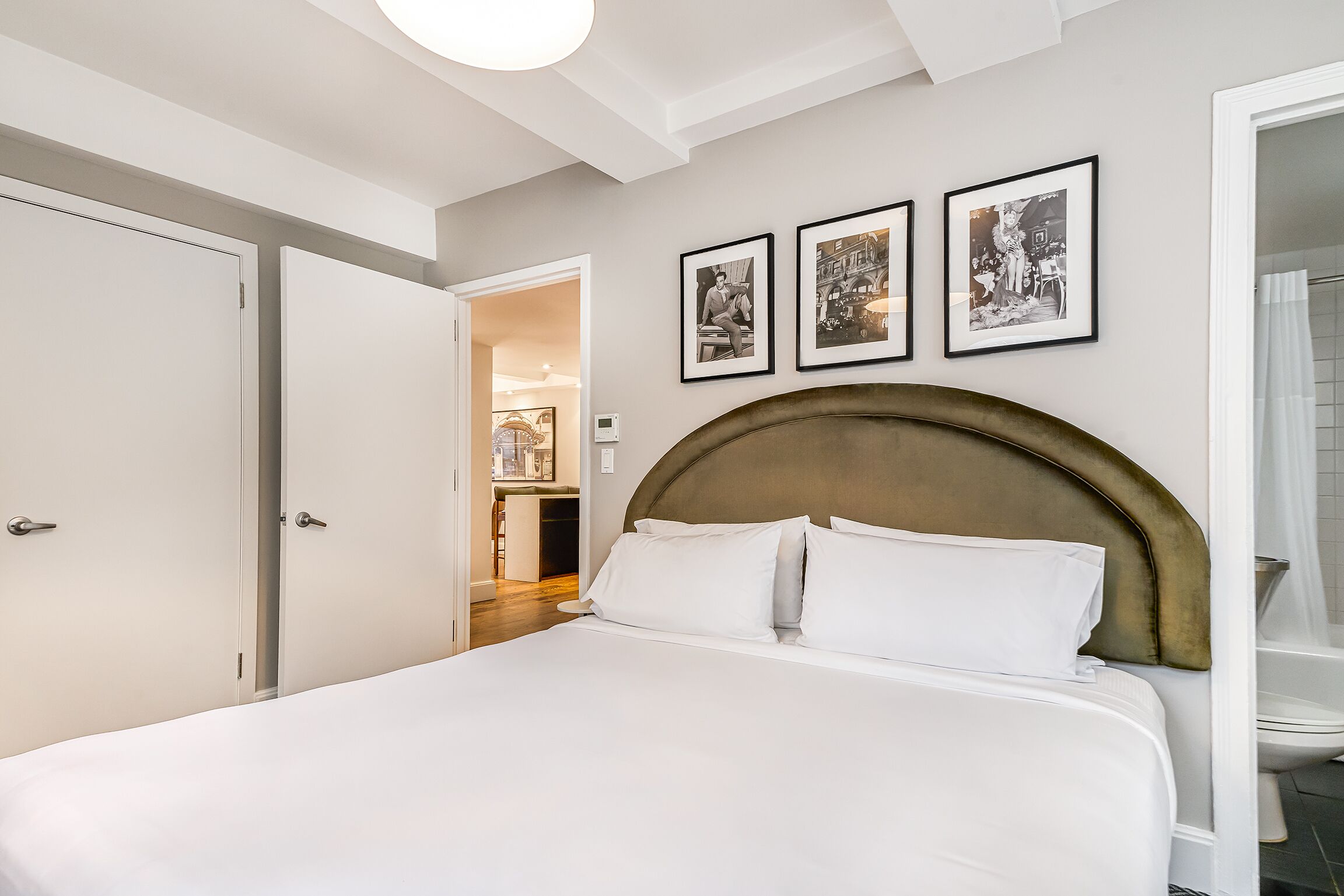 A bedroom with a large bed, a wooden headboard, and three framed pictures on the wall.