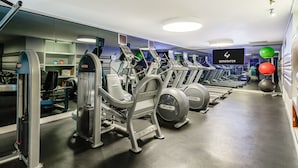 A gym with treadmills, elliptical machines, and exercise balls.