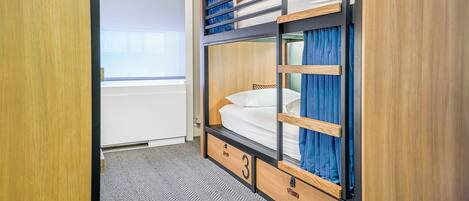 Une chambre avec un lit superposé, une fenêtre, une porte et un sol recouvert de moquette.