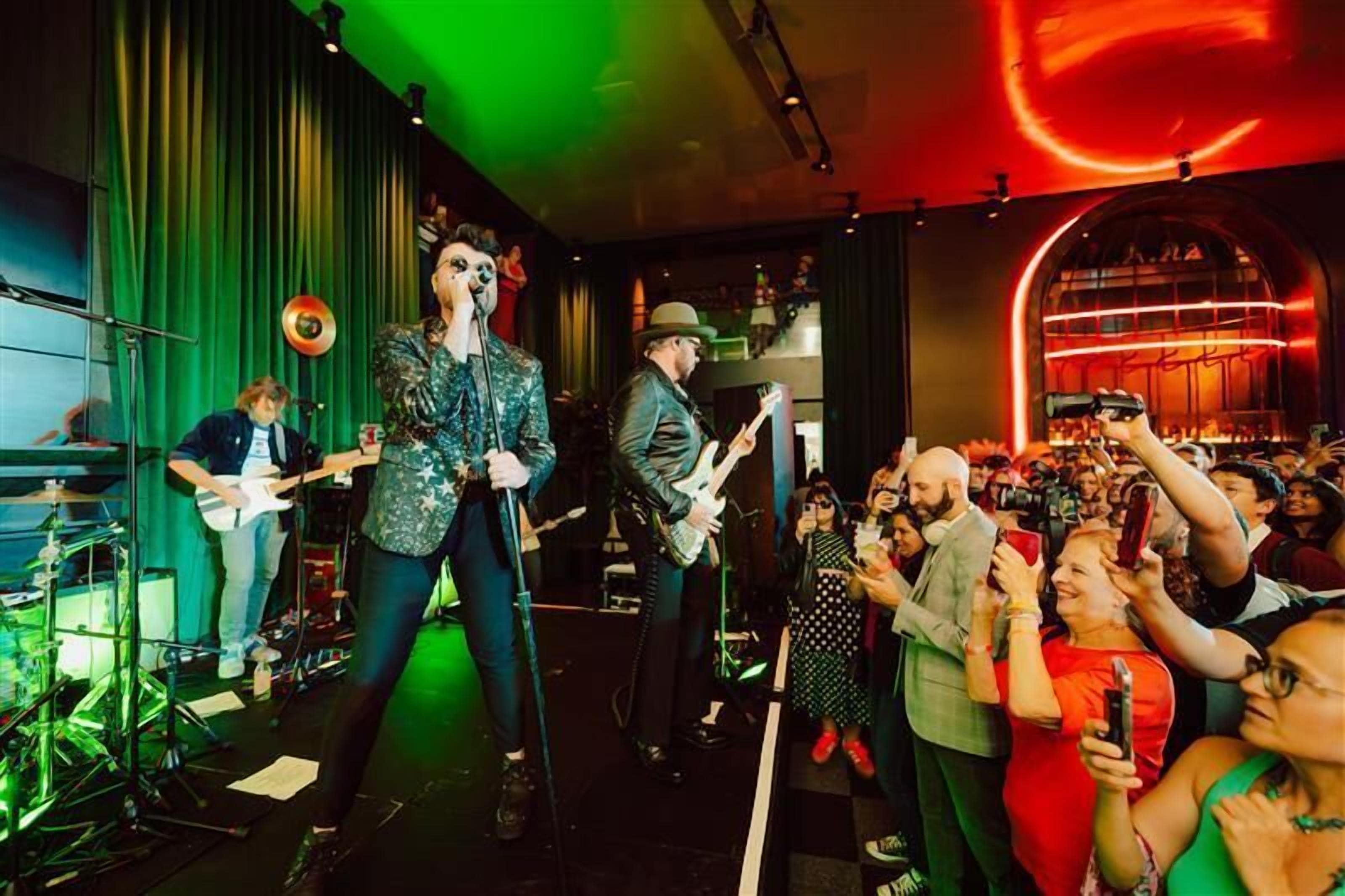 A band performing on stage with a crowd of people in the background.