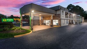 A hotel with a covered outdoor area, a sign for Quality Inn by Choice Hotels, and a stone facade.