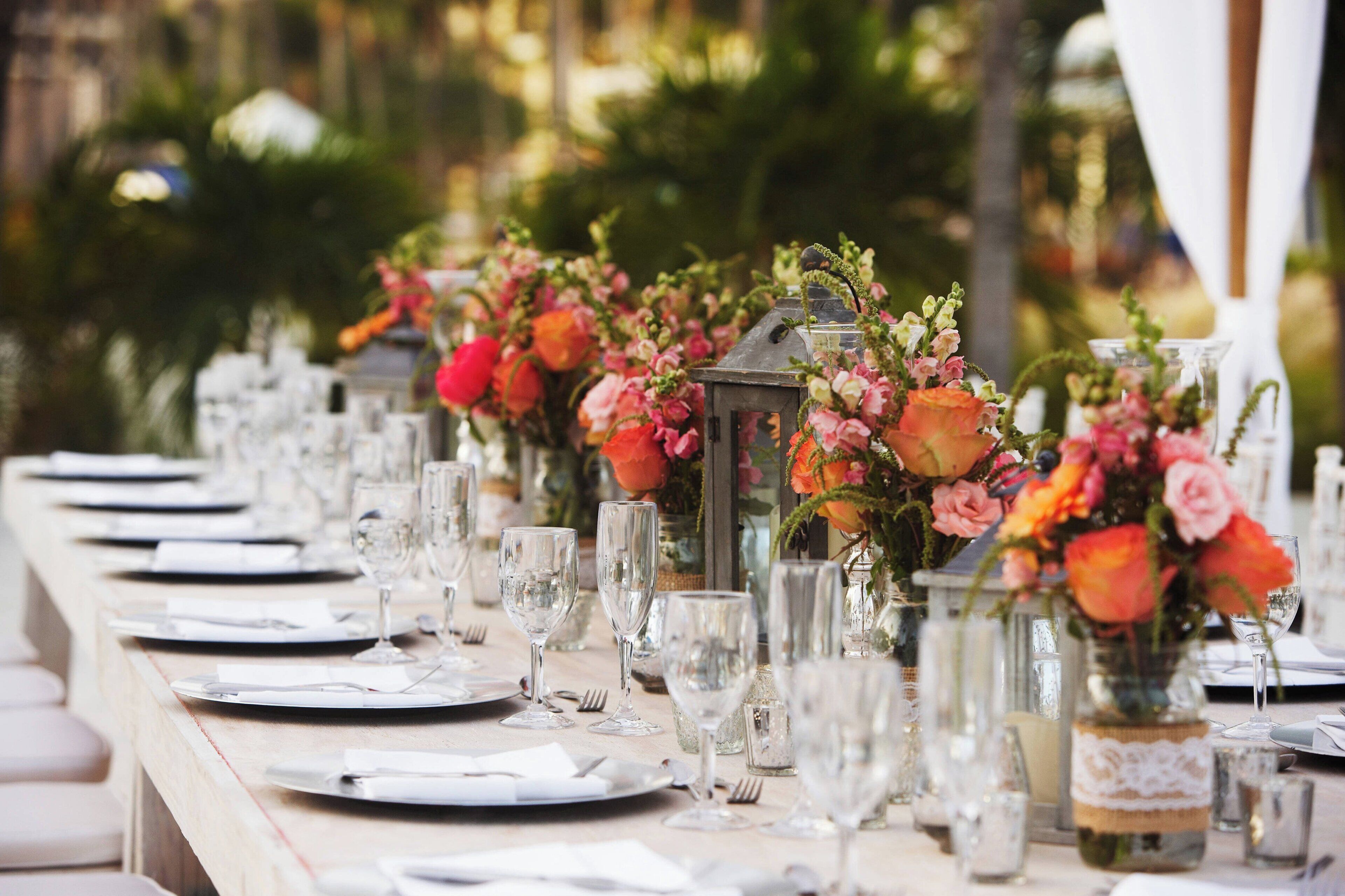 A long table set for a formal event with glassware, plates, and floral centerpieces.