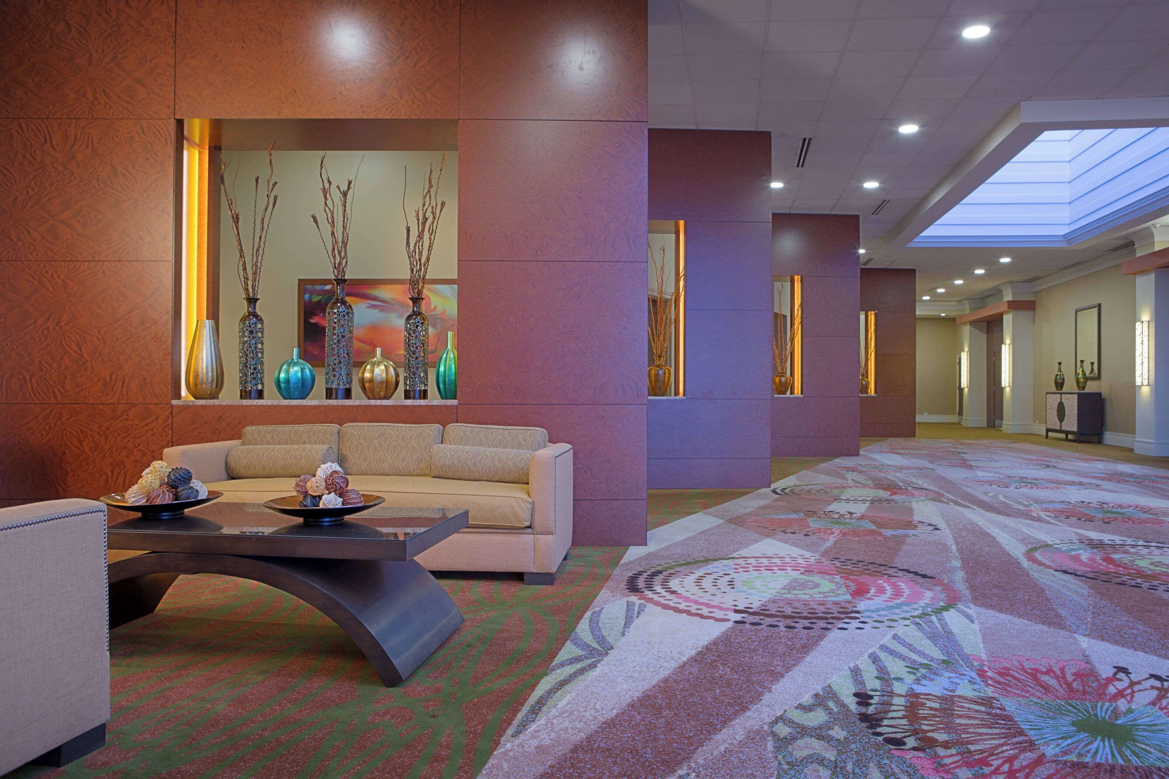 A lobby with a sofa, a coffee table, decorative vases, and a patterned carpet.