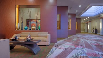 A lobby with a sofa, a coffee table, decorative vases, and a patterned carpet.