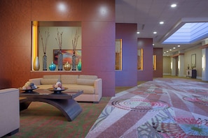A lobby with a sofa, a coffee table, decorative vases, and a patterned carpet.