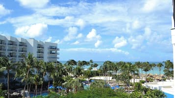 A resort with a pool, palm trees, and a view of the ocean.