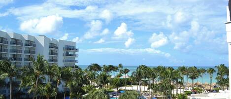 A resort with a pool, palm trees, and a view of the ocean.