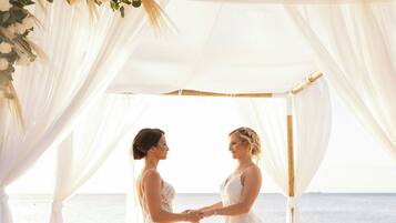 Decoración de boda en la playa, con toldo y adornos florales.