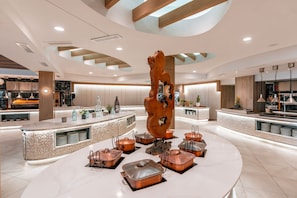 A modern kitchen with a central island, copper cookware, and a unique wooden sculpture.