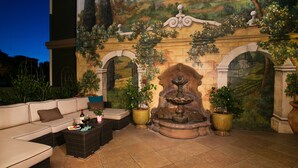 An outdoor patio area with a sofa, coffee table, and potted plants.