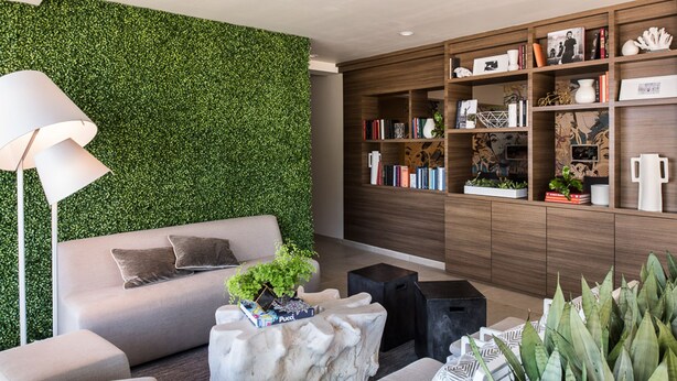 A modern living room with a green wall, a sofa, a coffee table, a bookshelf, and a lamp.