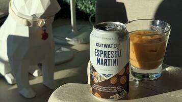 Uma lata de Cutwater Espresso Martini e um copo de café gelado sobre uma mesa.
