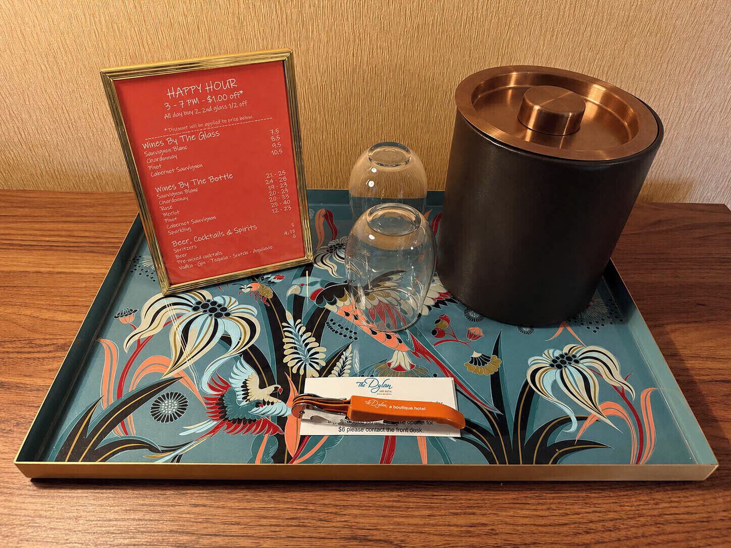 Una bandeja con un menú, un abrelatas, un vaso y un candelabro sobre una mesa.