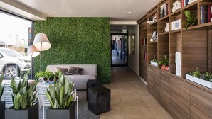 A modern reception area with a green wall, a sofa, a lamp, and a bookshelf.