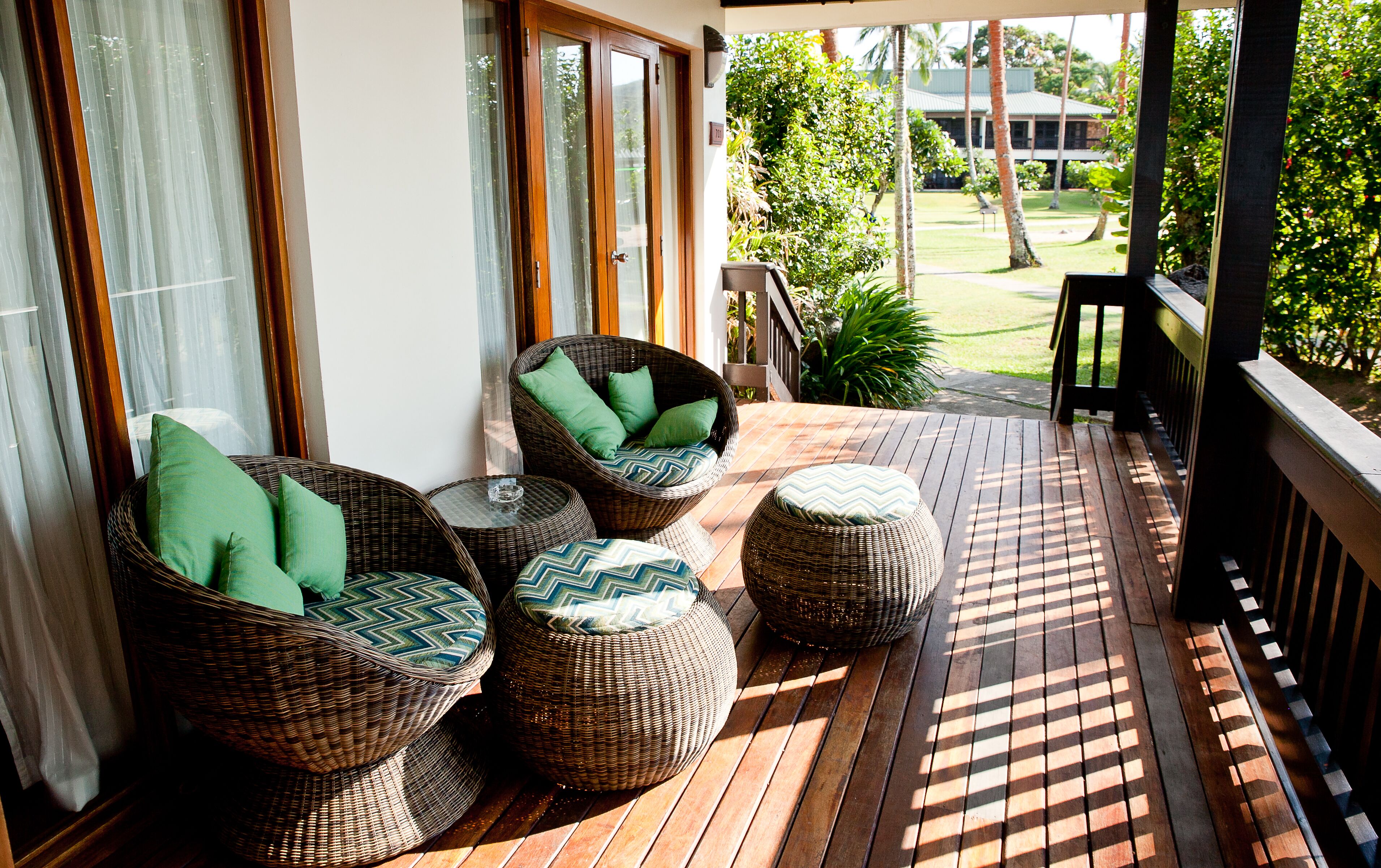 A covered outdoor seating area with wicker furniture and a wooden deck.