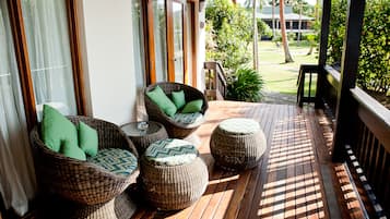 A covered outdoor seating area with wicker furniture and a wooden deck.