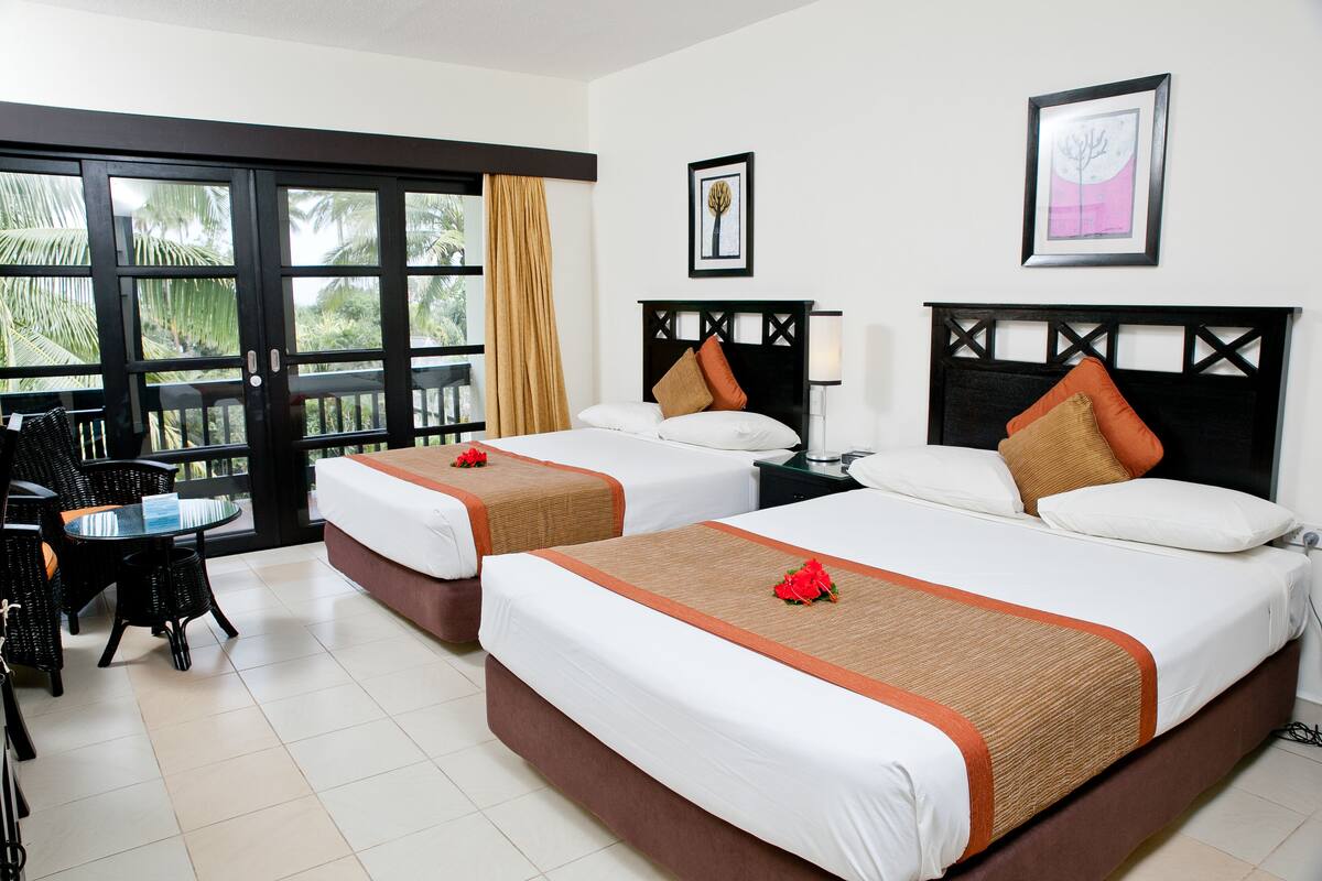 Habitación de hotel con dos camas, un balcón y una zona de comedor.