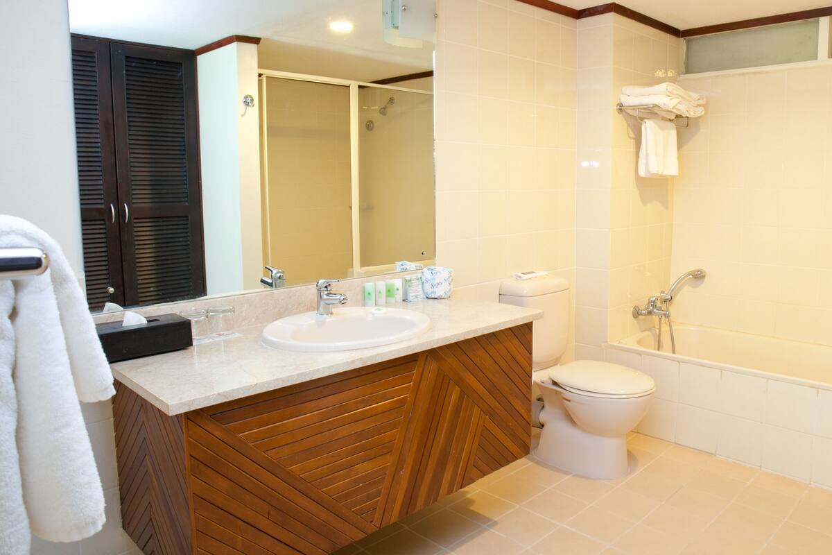 Un baño con tocador de madera, lavabo, inodoro y ducha.