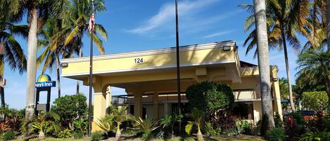 A yellow building with the number 124, surrounded by palm trees and a well-maintained garden.