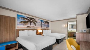 A hotel room with two beds, a desk, a chair, a painting of a beach, and a bathroom visible through an open door. - Days Inn by Wyndham Florida City (Florida City)