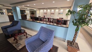 A lobby with two patterned armchairs, a reception desk, and a large potted plant. - Days Inn by Wyndham Florida City (Florida City)