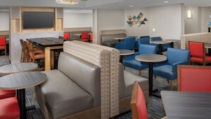 A hotel dining area with booths, tables, and a large screen.