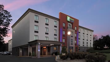 A Holiday Inn Express hotel with a modern design, featuring a prominent entrance, a covered parking area, and a landscaped front yard.