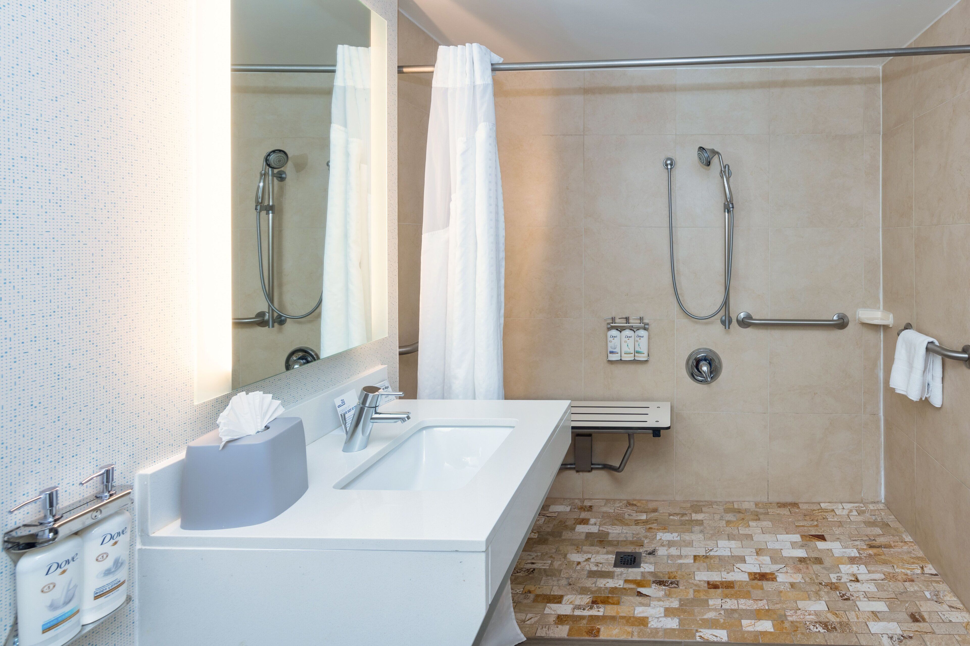 A modern bathroom with a sink, mirror, shower, and tiled floor.