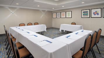 A conference room with two long tables, chairs, and framed artwork on the walls.