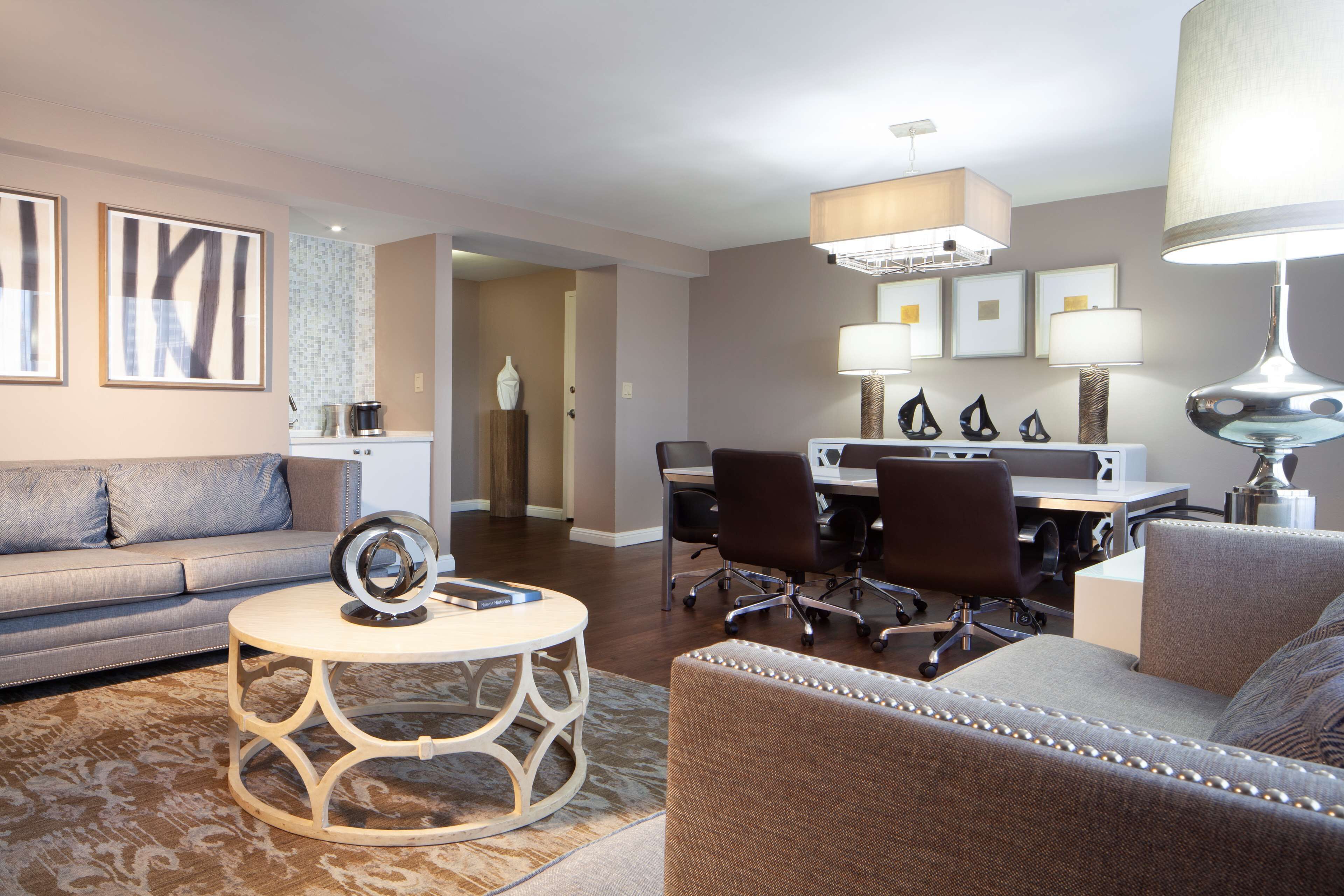 A modern living room with a sofa, a round coffee table, and a dining area with a table and chairs.