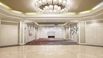 Un pasillo amplio y luminoso con una gran araña, un suelo con diseño y una pared decorada con cuadros.