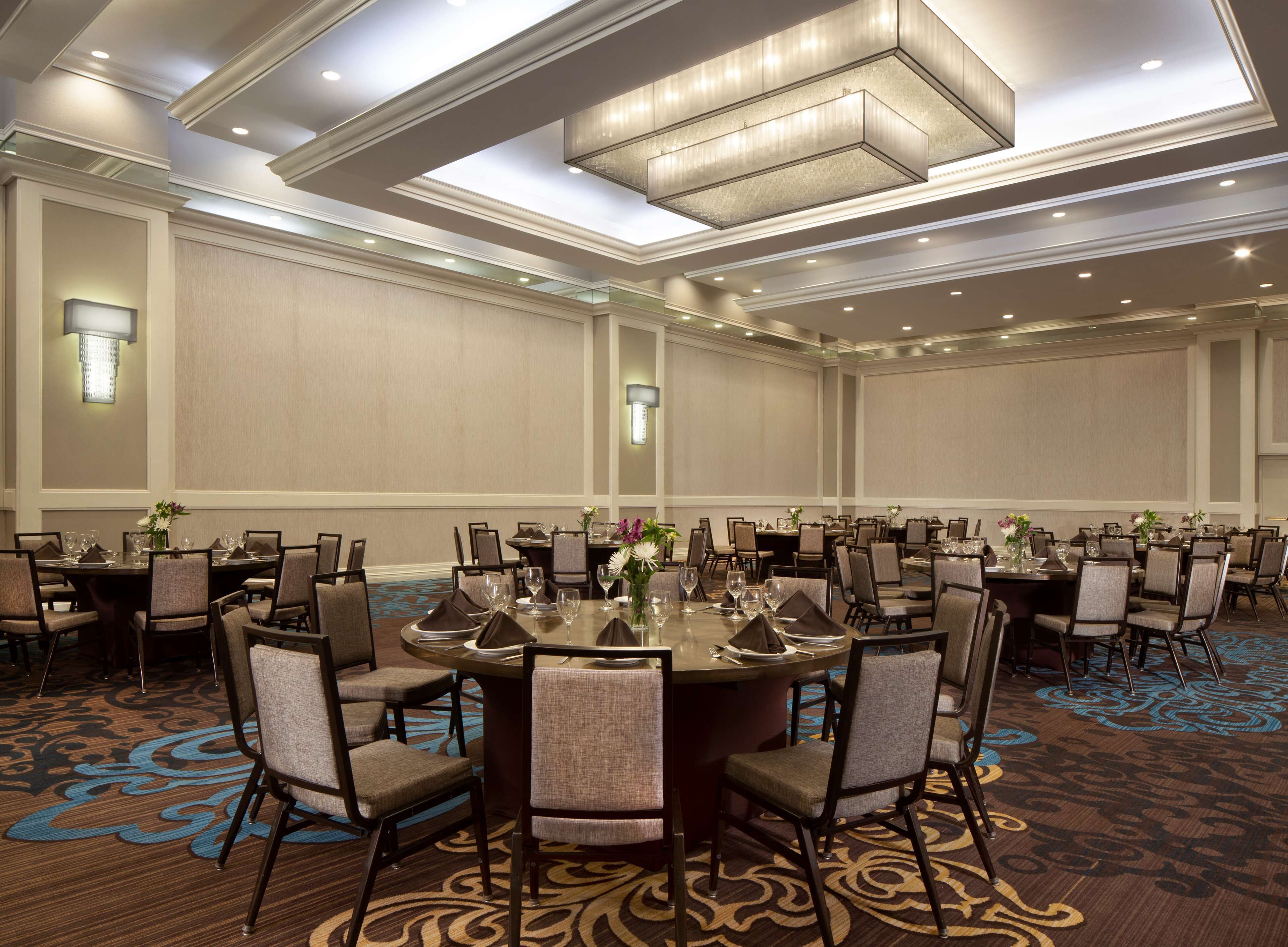 A large conference room with round tables, chairs, and a carpeted floor.