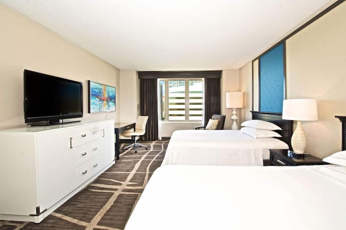 A hotel room with a bed, a TV, a desk, and a chair.