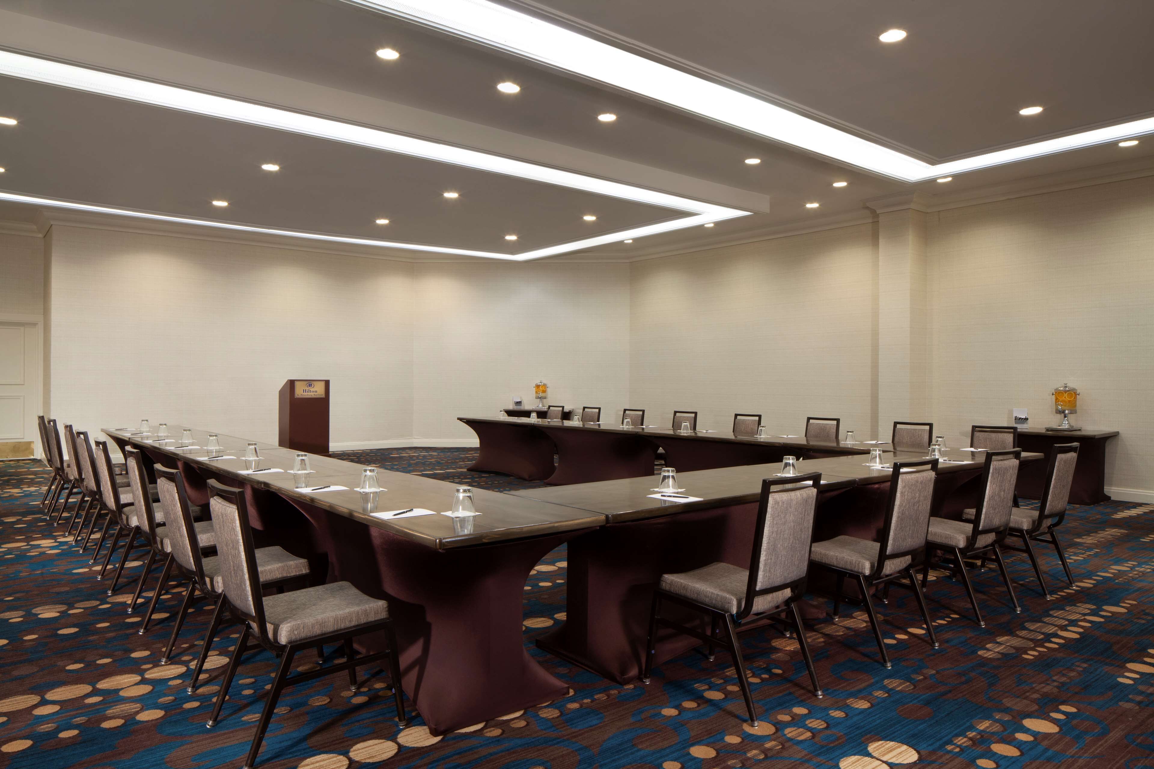 A conference room with a long table, chairs, and a carpeted floor.
