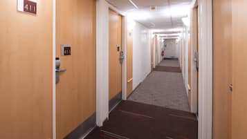 A hotel corridor with wooden doors, each marked with a number.