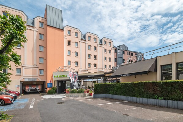 A hotel with a modern design, featuring a parking area and a well-maintained exterior.