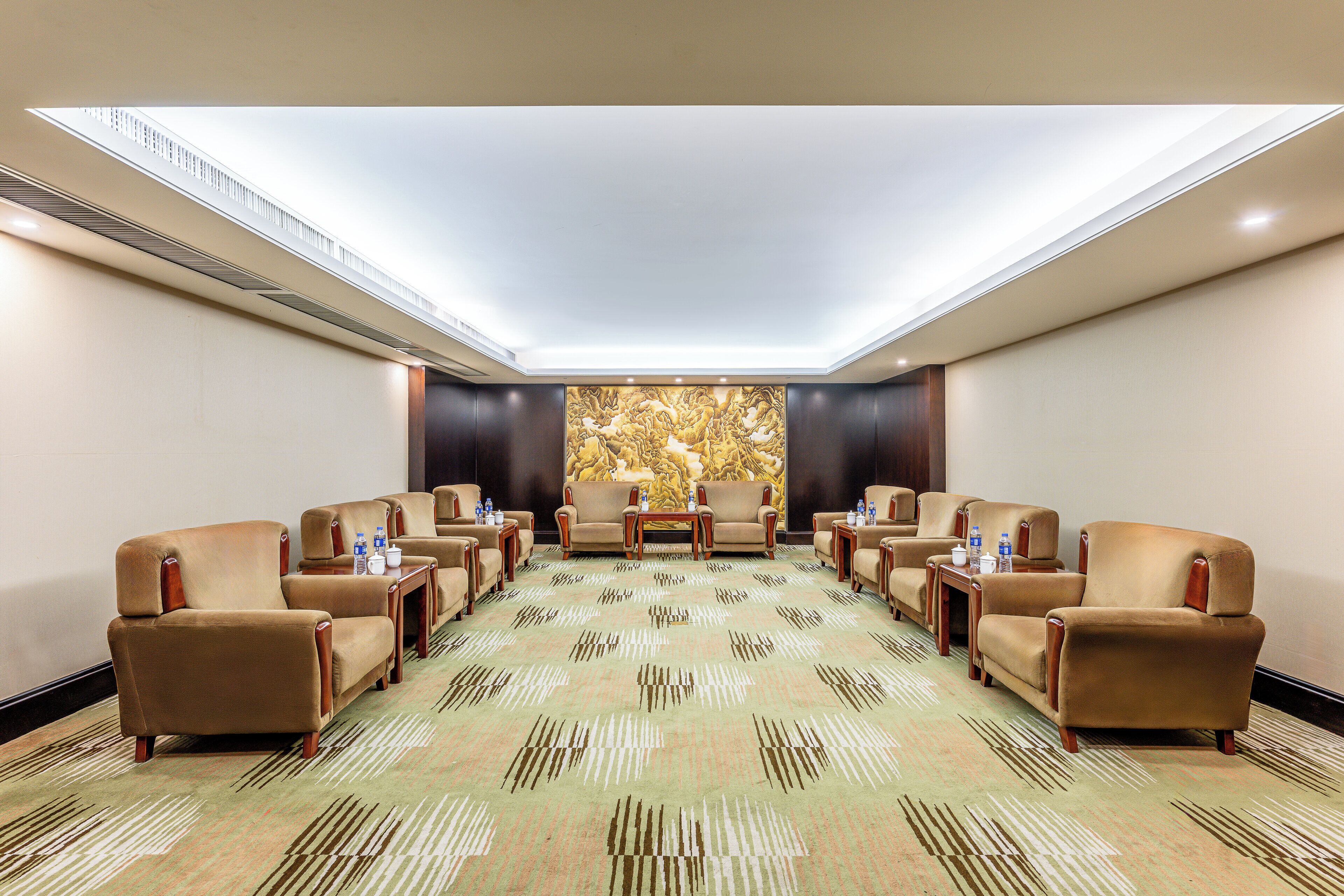 A conference room with a patterned carpet, beige armchairs, and a large wall mural.