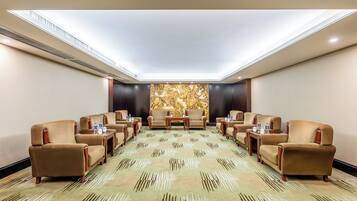 A conference room with a patterned carpet, beige armchairs, and a large wall mural.