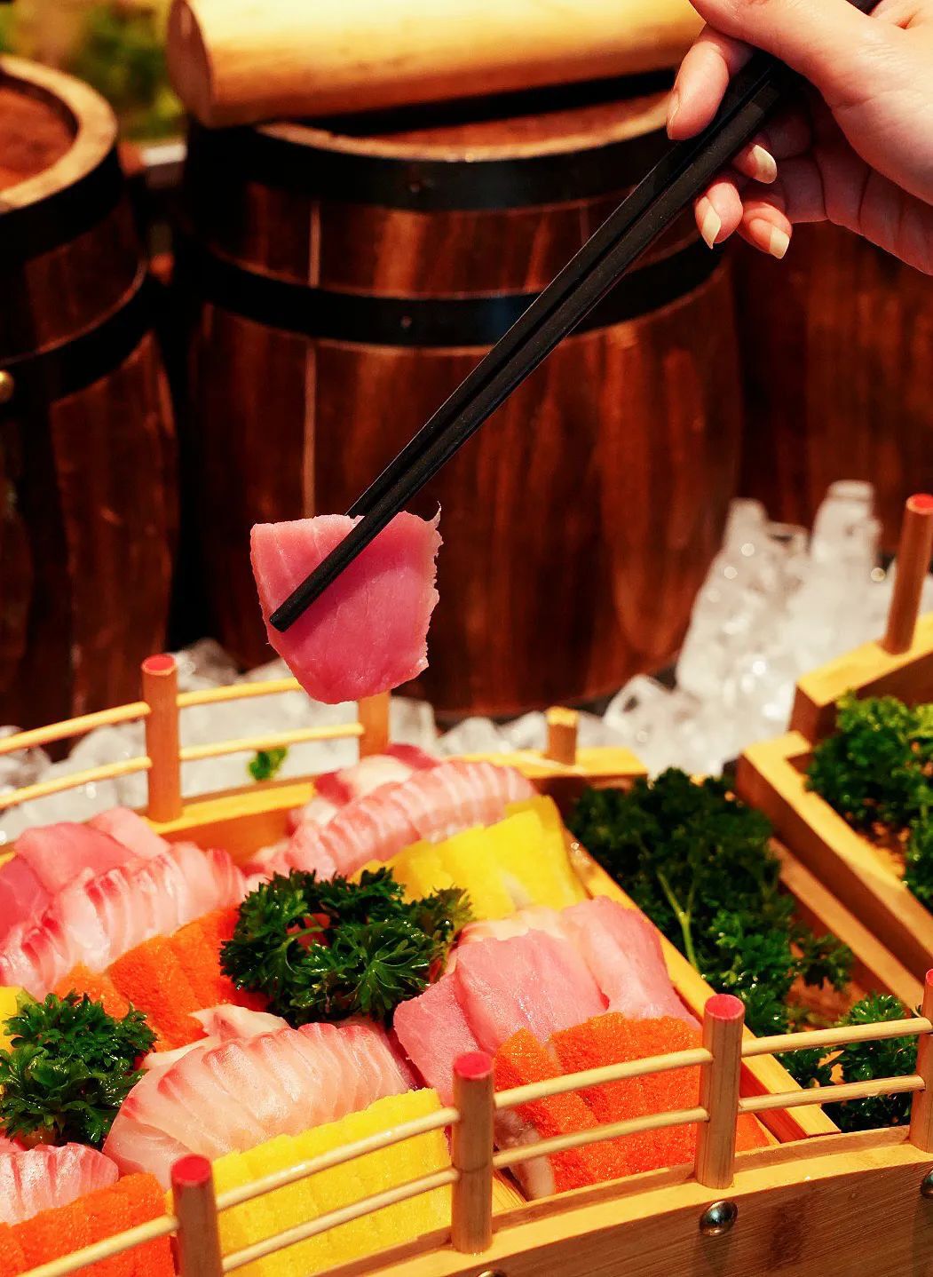 Un plateau de sushis composé de différents types de poisson, garni de persil, et servi sur un présentoir en bois avec des baguettes.
