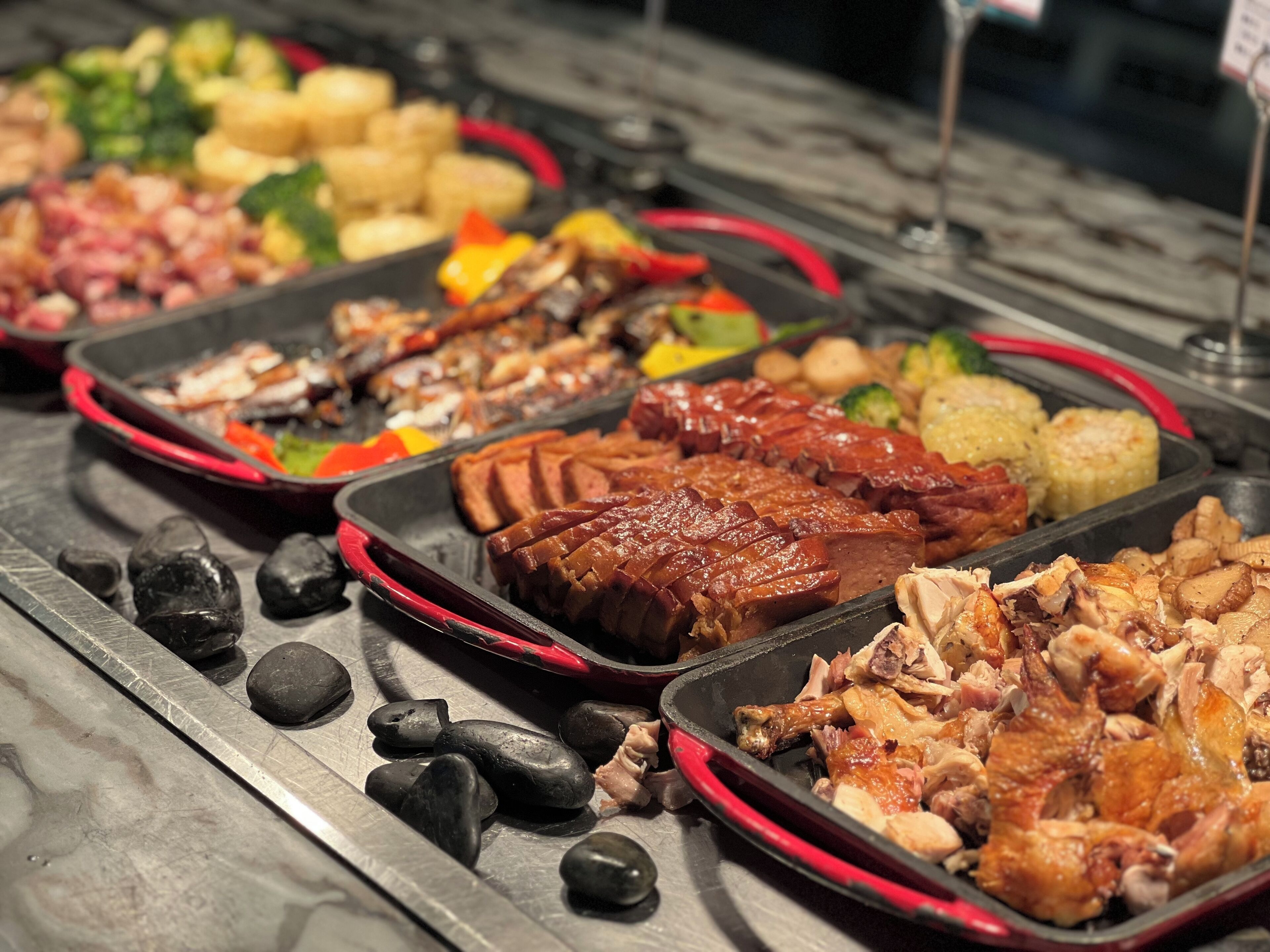 A buffet with various dishes including meats, vegetables, and potatoes.