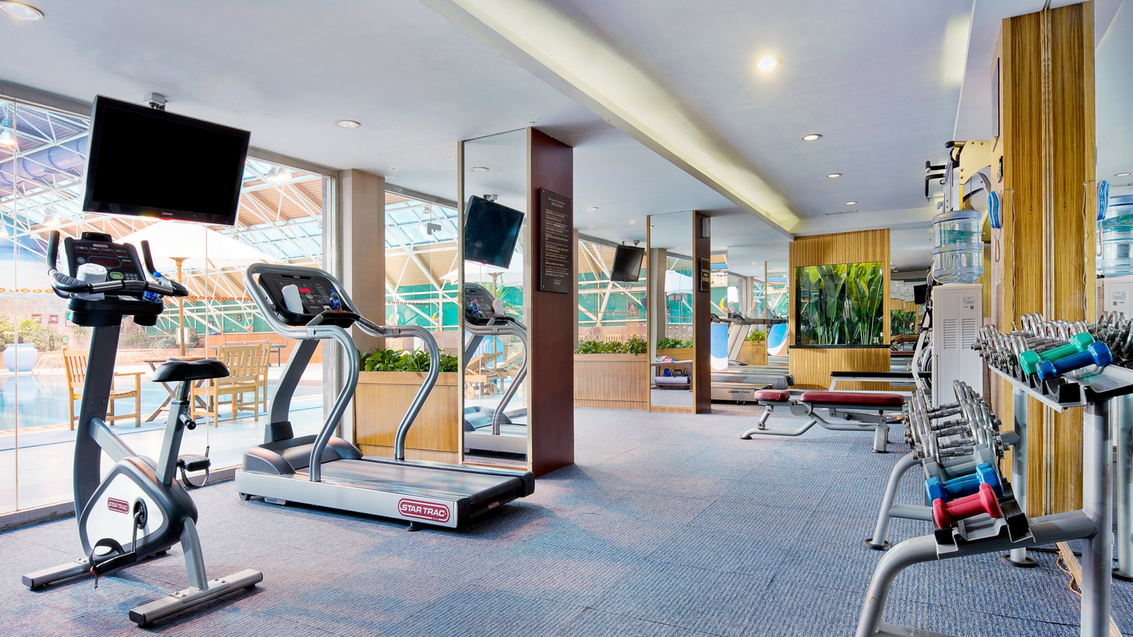 Un gimnasio con cintas de correr, bicicletas estáticas y máquinas de pesas.
