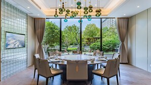 A dining area with a round table, chairs, and a view of greenery outside. - Crowne Plaza Zhengzhou by IHG (Zhengzhou)