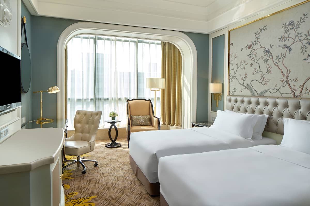 Une chambre d’hôtel avec deux lits, un bureau, une chaise et un téléviseur.