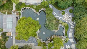 An aerial view of a landscaped area with a central pond, stone pathways, and surrounding greenery. - Crowne Plaza Zhengzhou by IHG (Zhengzhou)
