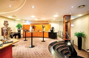 Un hall d’hôtel comprenant un comptoir d’accueil, une table de baby-foot, une machine à café et un escalier.