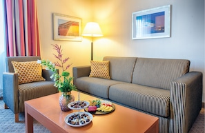 Ett modernt vardagsrum med randiga soffor, ett soffbord med snacks och en lampa.