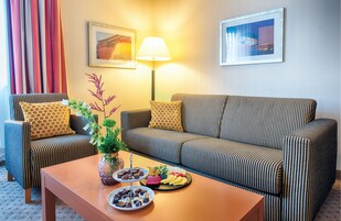 A modern living room with striped sofas, a coffee table with snacks, and a lamp.